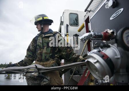 A U.S. Air Force fire protection specialist assigned to the 673d Civil Engineer Squadron, secures fire hoses after completing wartime-firefighting readiness training at Joint Base Elmendorf-Richardson, Alaska, Aug. 23, 2018. During the readiness training the Air Force firefighters donned various levels of mission oriented protective posture (MOPP) gear and practiced responding to emergency situations in a simulated toxic environment during a chemical, biological, radiological, or nuclear strike. Stock Photo