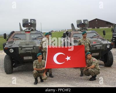 Turkish soldiers from KFOR Multi-National Battle Group - East's Turkish Infantry Company display Turkey's colors in front of Cobra armored vehicles at Camp Bondsteel, Kosovo, Aug. 28. Stock Photo