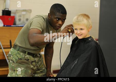 This youngster is all smiles as Spc. Tedrick J. Jackson cuts his hair during Back-to-School night at Edgewood Elementary School in Edgewood, Md., Aug. 30. Jackson, an information tech specialist with the 20th CBRNE Command, was one of several Soldiers from the 20th who participated in welcoming students as they start the new school year. Stock Photo