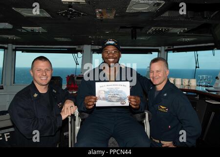 PACIFIC OCEAN (Aug. 29, 2018) Yeoman Seaman Apprentice Julian Robinson, center, from Clinton, Maryland, poses for a photograph as the Sailor of the Day with Commanding Officer Capt. Randy Peck, right, and Command Master Chief Benjamin Rushing aboard the Nimitz-class aircraft carrier USS John C. Stennis (CVN 74). John C. Stennis is underway conducting routine operations in the U.S. 3rd Fleet area of operations. Stock Photo