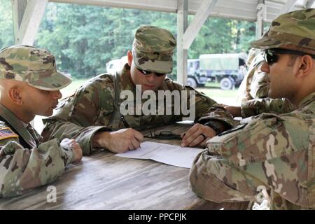 U.S. Army Sgt. Guillermo Ortiz of San Juan, Puerto Rico, a team leader with the 246th Quartermaster Company, locates a point on a map as part of a land navigation test at Fort Pickett, Va., Aug. 12, 2018. More than 300 Army Reserve Soldiers from across the nation attended the Mortuary Affairs Exercise, which also included marksmanship, search and recovery operations and other training. Stock Photo