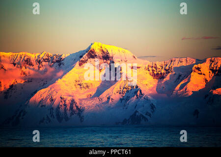 Evening light over mountains from the Gerlache Strait separating the Palmer Archipelago from the Antarctic Peninsula off Anvers Island. The Antartic Peninsula is one of the fastest warming areas of the planet. Stock Photo