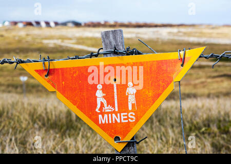 A warning sign about the presence of Argentinian mines on the Falkands, left over from the 1980's Falklands conflict when Argentina invaded the islands, with houses behind. Stock Photo