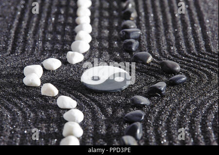 Zen garden with yin and yang stones in black sand Stock Photo