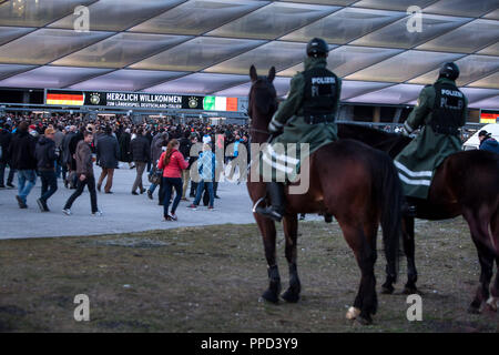 On their way to the Allianz Arena, spectators are watched by two mounted policemen prior to the soccer match Germany - Italy. Stock Photo