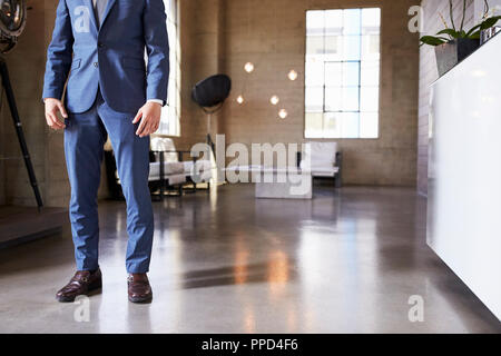 Low section of man in suit standing in modern furnished room Stock Photo