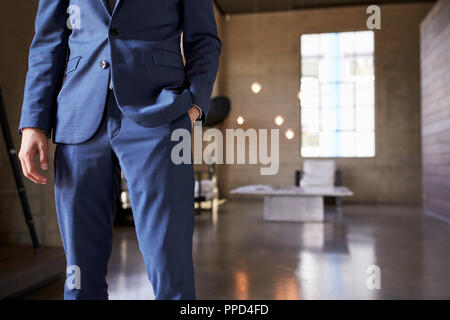 Mid section of man in blue suit standing, hand in pocket Stock Photo