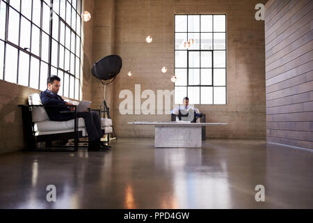 Two men sitting in the foyer of a business building Stock Photo