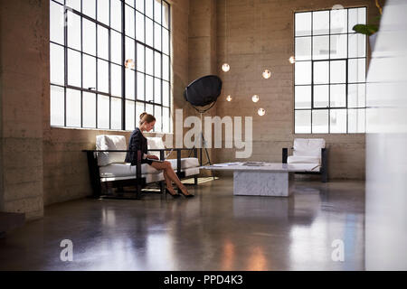 Young businesswoman using laptop in business foyer Stock Photo