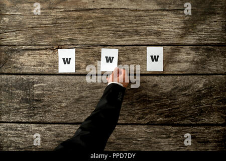 High angle view of web developer placing three white papers spelling WWW on a textured rustic wooden planks. Conceptual of internet web professionals. Stock Photo