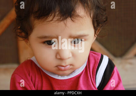 Closeup-up portrait of a little adorable sad caucasian boy thinking sadly, wearing pink cloths Stock Photo
