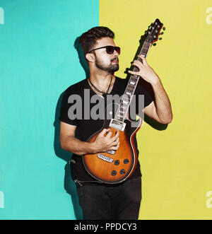 Closeup Portrait of one handsome passionate expressive cool young brunette rock musician men playing electric guitar standing against Paste background Stock Photo