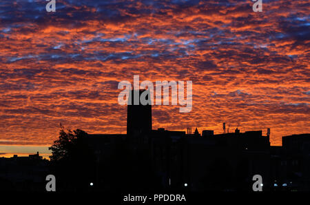 The sky behind Liverpool's Anglican Cathedral turns orange and red before the sun rises over the city. Stock Photo