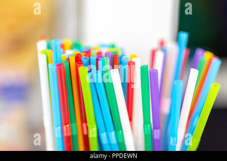 Bunch of colorful plastic sipping straws in wooden box at cafe counter. Drinks decoration and accessories. Bright multicolored background. Stock Photo