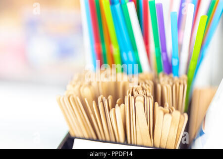 Bunch of wooden stir sticks and colorful plastic sipping straws in box at cafe counter. Drinks decoration and accessories. Bright multicolored backgro Stock Photo