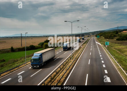 Caravan or convoy of lorry trucks in line on a country highway Stock Photo