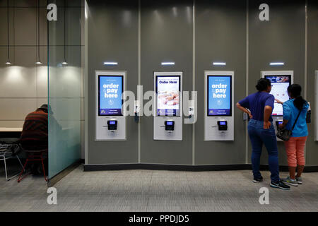 People at a self-service digital ordering kiosk in a McDonalds Stock Photo