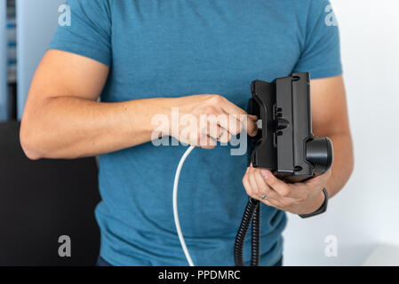 VoIP Telephony, technical support, services. Specialist connects the phone to the network Stock Photo
