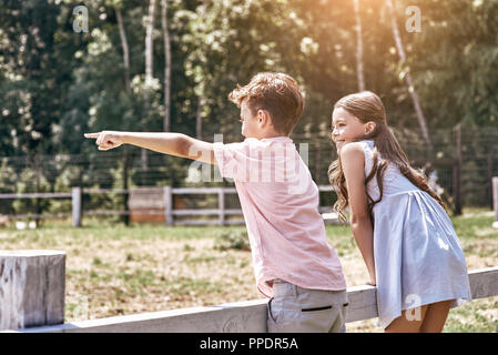 Friendship. Little boy pointing aside while girl looking curious Stock Photo