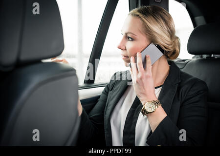 Businesswoman sitting in car talking on cellphone Stock Photo