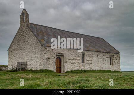The 12th century St Cwyfan Church, on the small tidal island of Cribinauon, on Anglesey. Stock Photo