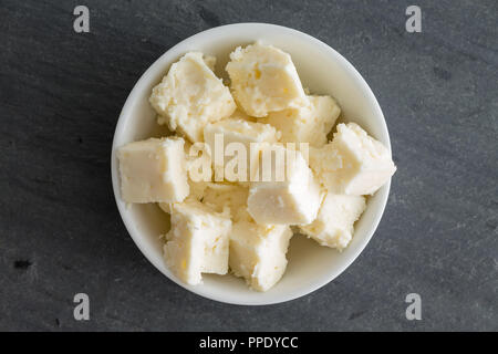 Bowl of creamy crumbly traditional Feta cheese made with sheep and goats milk and cured in brine viewed centered on slate from above Stock Photo