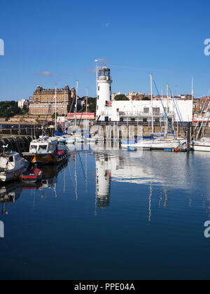 The lighthouse reflected in the harbour from East Pier at Scarborough North Yorkshire England Stock Photo