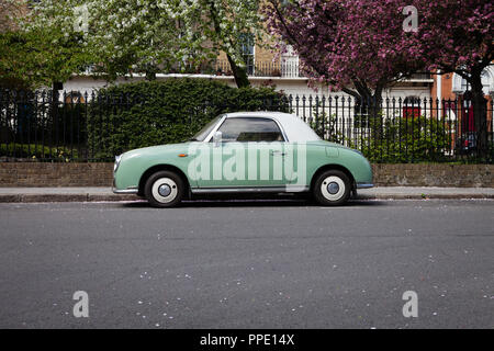 Nissan Figaro parked in front of trees in blossom, Islington, London. Stock Photo