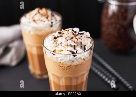 Iced latte coffee in a tall glass with caramel and chocolate syrup and whipped cream. Stock Photo