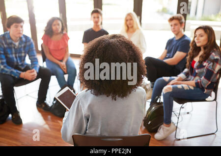Rear View Of Female Tutor Leading Discussion Group Amongst High School Pupils Stock Photo