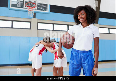 Portrait Of Female High School Basketball Coach With Team Huddle In Background Stock Photo