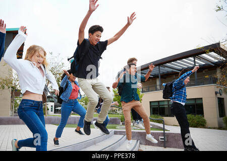 Group Of High School Students Jumping In Air Outside College Buildings Stock Photo