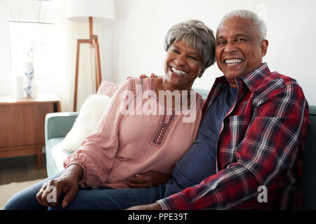 Portrait Of Loving Senior Couple Relaxing On Sofa At Home Stock Photo
