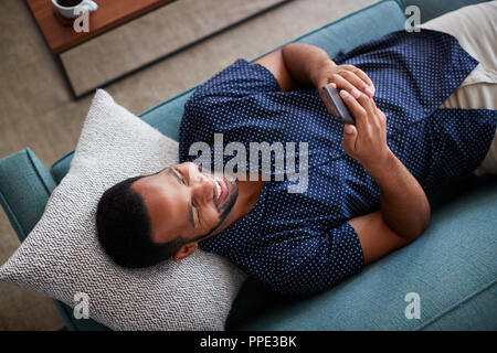 Overhead View Of Man Lying On Sofa At Home Using Mobile Phone Stock Photo