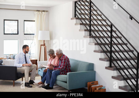 Senior Couple Meeting With Male Financial Advisor At Home Stock Photo