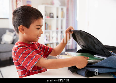 Boy In Bedroom Packing Bag Ready For School Stock Photo
