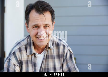 Portrait Of Senior Man Standing Outside Grey Clapboard House Stock Photo