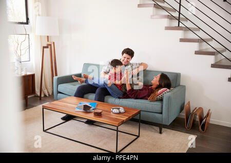 Family Having Fun Lying On Sofa At Home Together Stock Photo