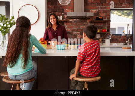 Mother Making School Lunches For Children In Kitchen At Home Stock Photo