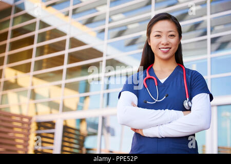 Smiling Asian female healthcare worker with arms crossed Stock Photo