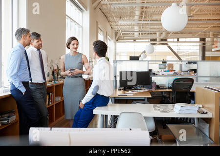 Female manager and colleagues talking in an open plan office Stock Photo