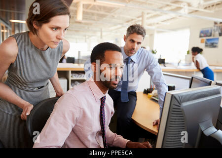 Three business colleagues working together around a monitor Stock Photo