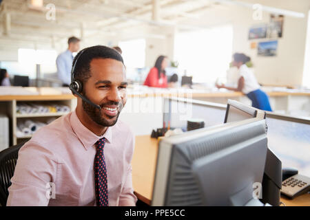 Smiling male call centre worker looking at screen, close-up Stock Photo