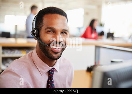 Man working in a call centre smiling to camera, close-up Stock Photo