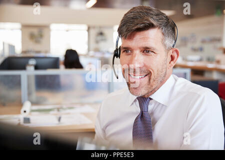 White male call centre worker looking at screen Stock Photo