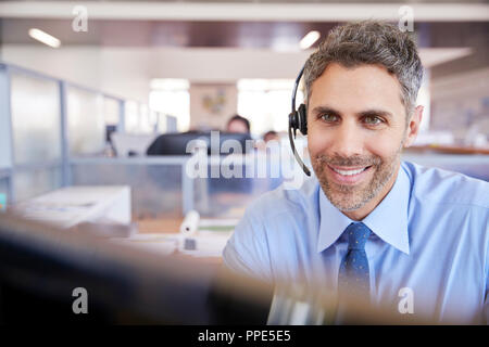 White male call centre worker looking at screen Stock Photo