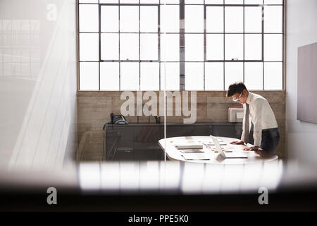 Businessman working alone in an office, seen through window Stock Photo