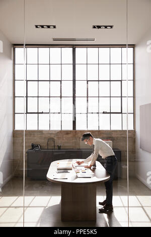 Businessman stands working alone in an office, vertical Stock Photo