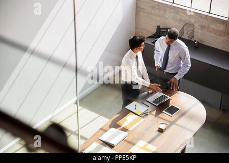 Two businessmen in discussion using laptop, elevated view Stock Photo