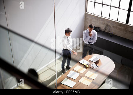 Two businessmen talk standing in an office, elevated view Stock Photo